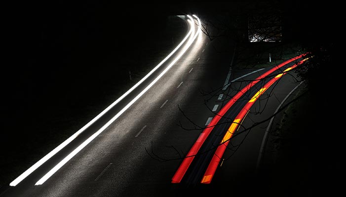 Zwei Autos zeichnen Lichtstreifen in die Nacht. Dieses Bild wurde 8 Sekunden belichtet. Ab Sekunde 0 wurde der sich entfernende Lastwagen (rot) aufgezeichnet, in Sekunde 8 war das entgegenkommende Auto auf selber Höhe wie der Lastwagen bei Sekunde 0. Das war reines Glück und hätten kaum so geplant werden können.